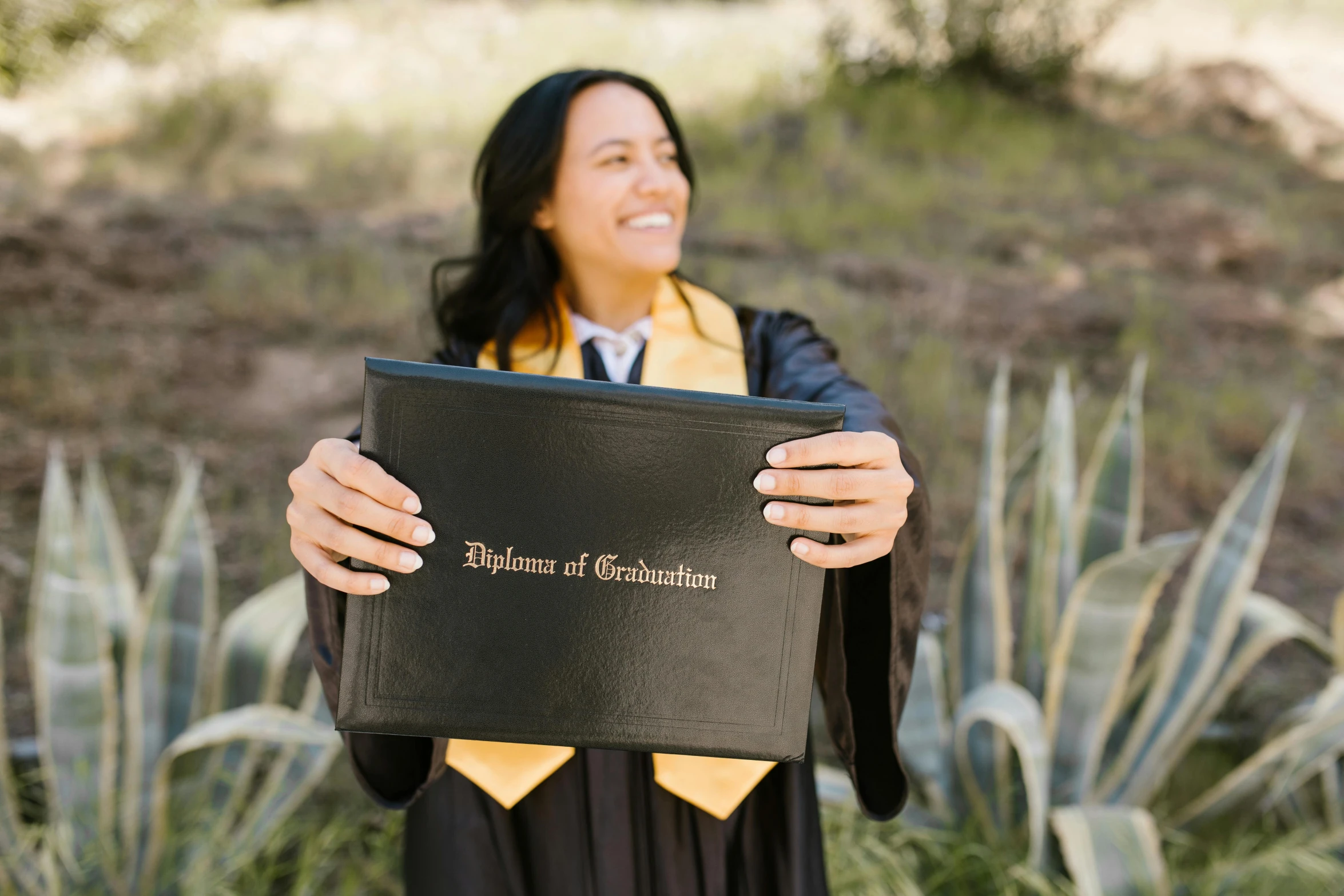 a person holding a black book in front of bushes