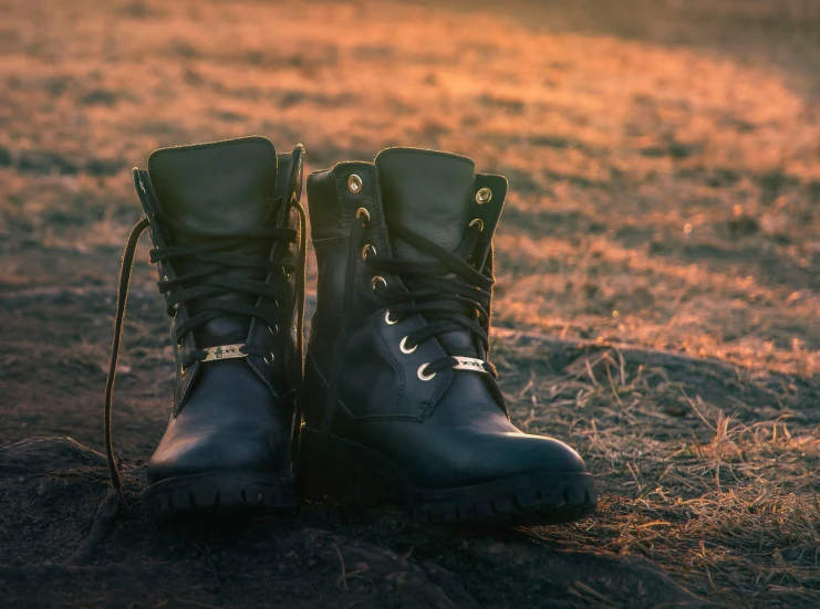 two pairs of black hiking boots standing on a dirt ground