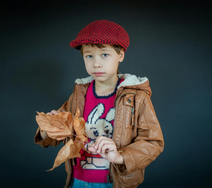 boy in brown jacket wearing red hat and brown jacket