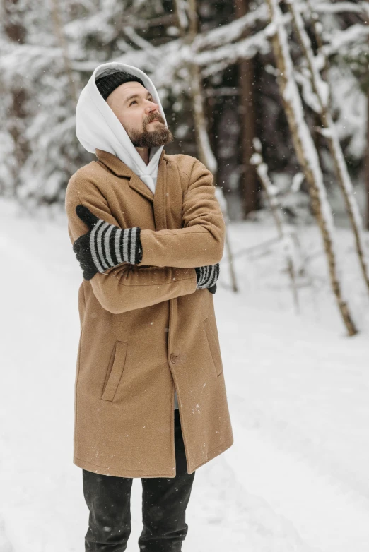 man in brown coat standing in the snow