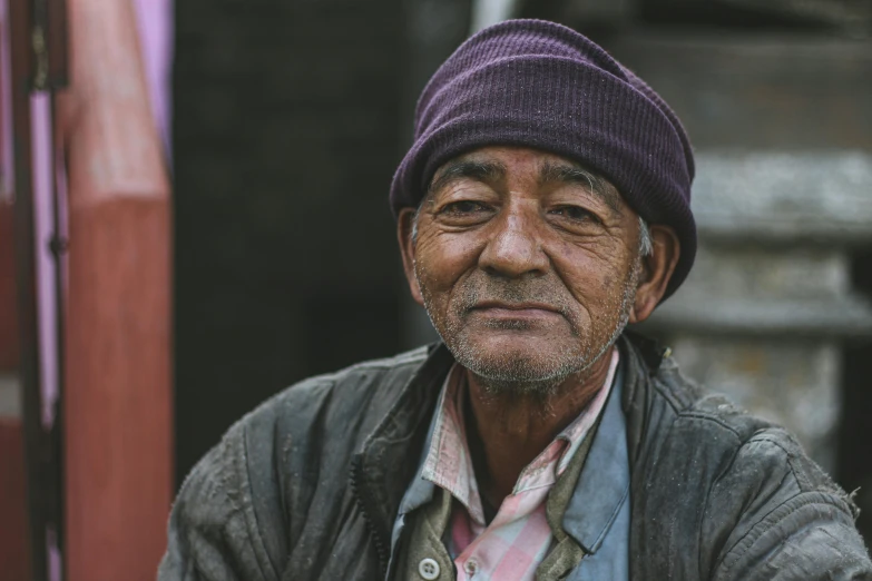 an old man is smiling while wearing a purple hat