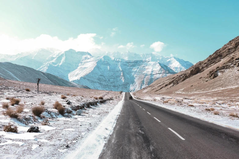 a lone car driving down the road in the snow