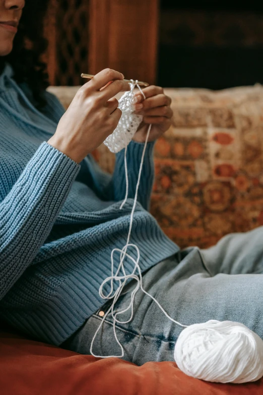 the woman is knitting on her lap with one hand