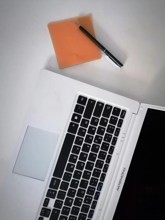 a laptop computer next to a cup of tea and note pad