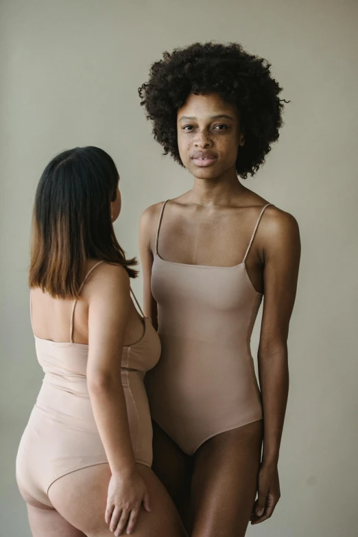 two women in  underwear standing and looking in a mirror