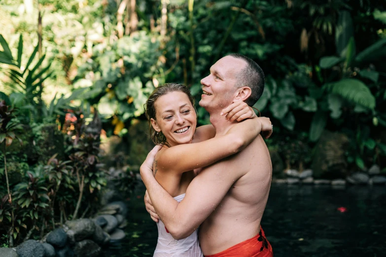 a man hugging a woman who is outside by the water