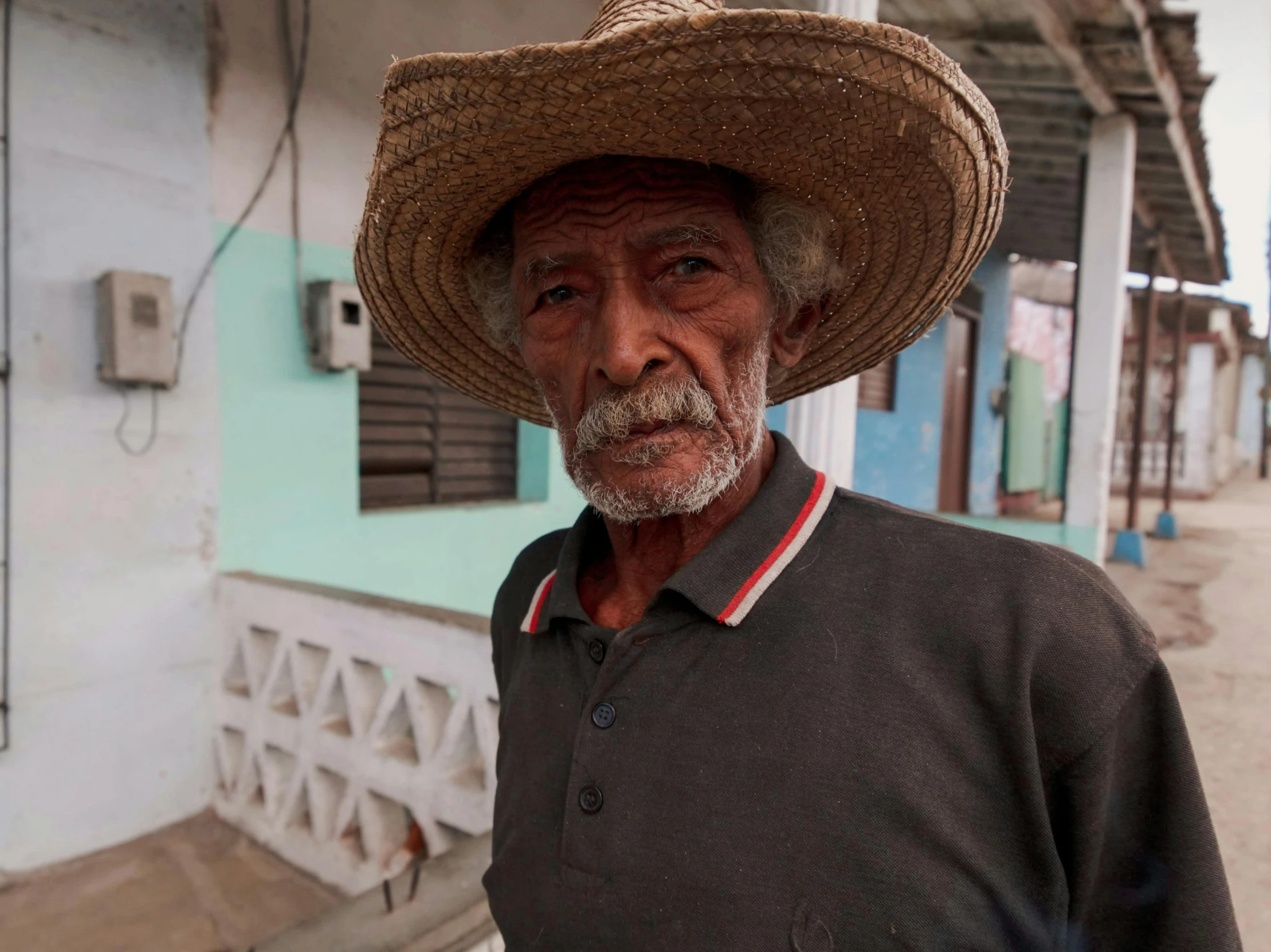 an older man in a hat standing in front of a building