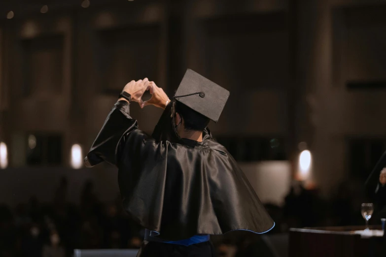 a person in a graduation cap and gown saluting