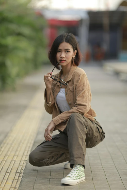 a young woman crouches down while smoking a cigarette