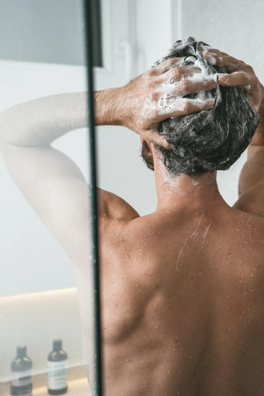 a shirtless man in the bathroom getting his hair shaved