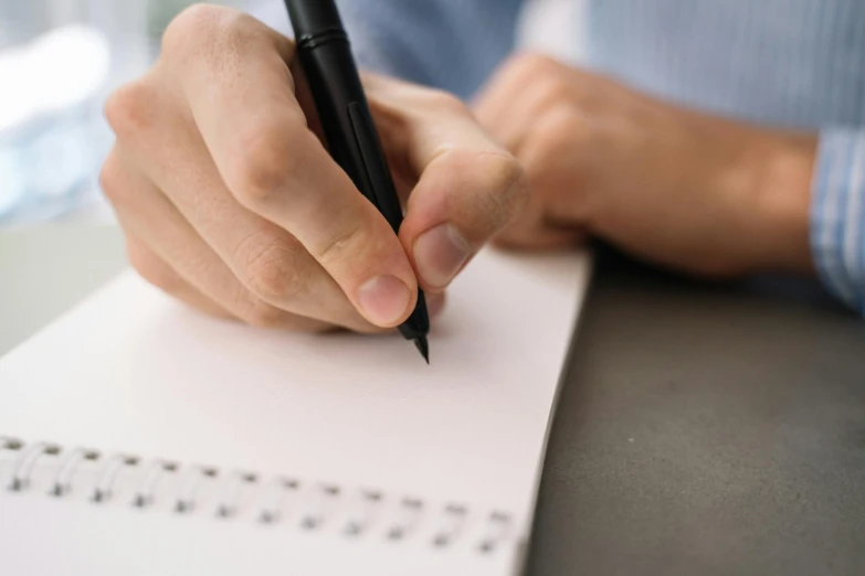 a man writing on a paper with a pen