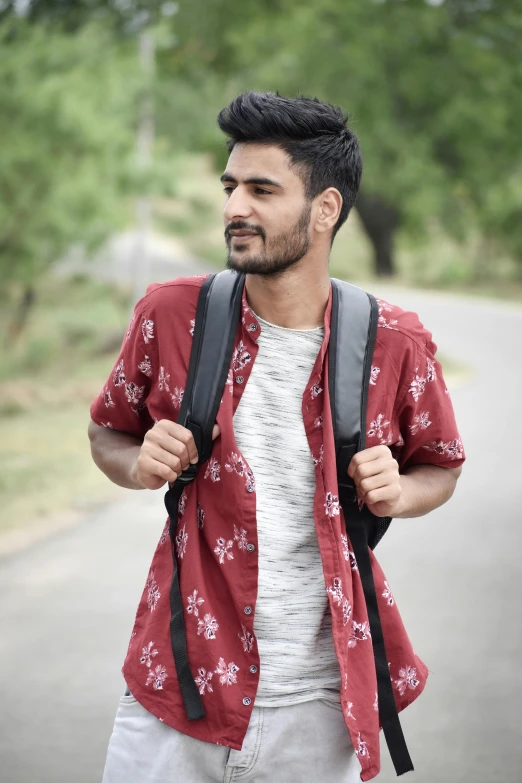 young man carrying a backpack standing on a road