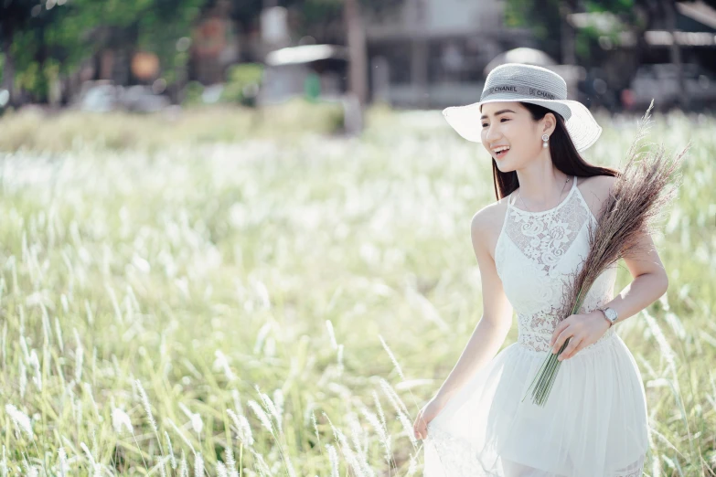 a woman in a field wearing a hat and holding a bouquet of flowers