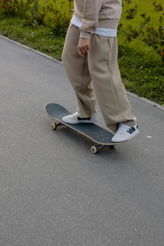 someone wearing white sneakers, khaki pants and a sweater skateboarding