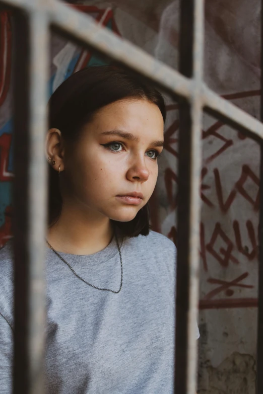 a close up of a young person behind bars