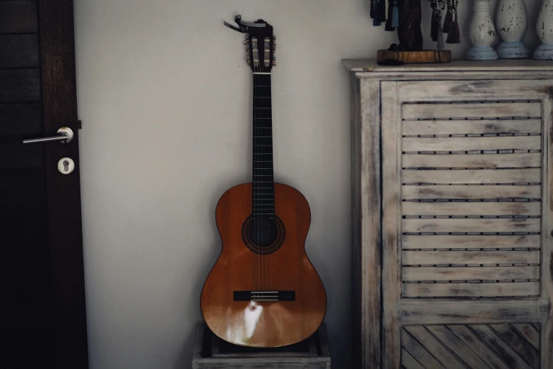 an acoustic guitar resting in the corner next to some vases