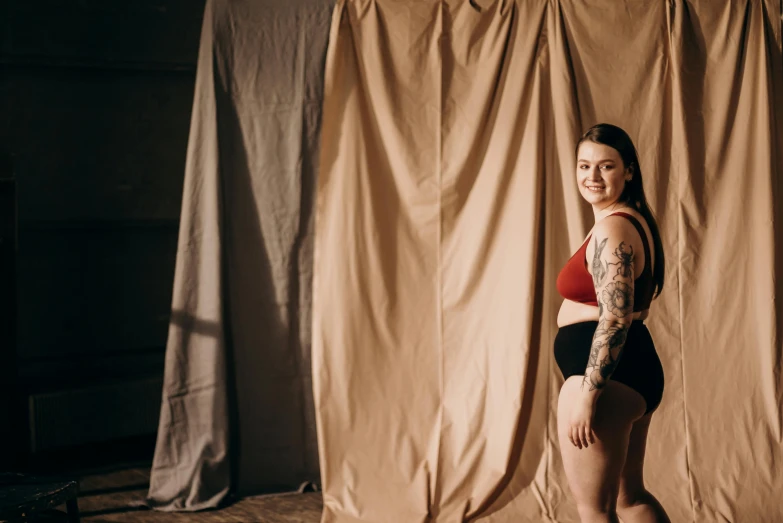 a woman in red and black panties standing next to a curtain