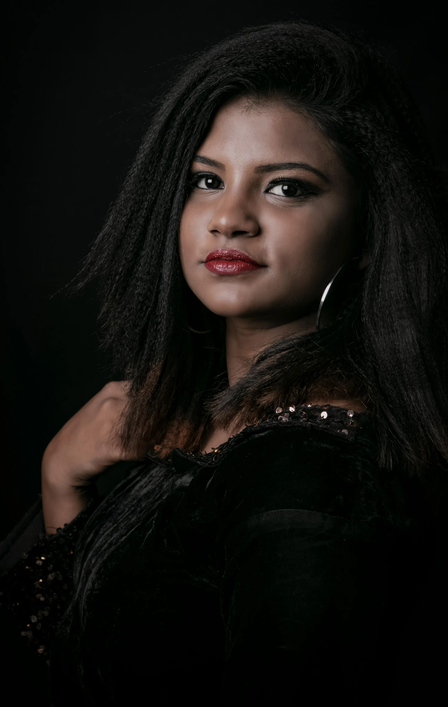 a woman wearing a dark dress and hoop earrings