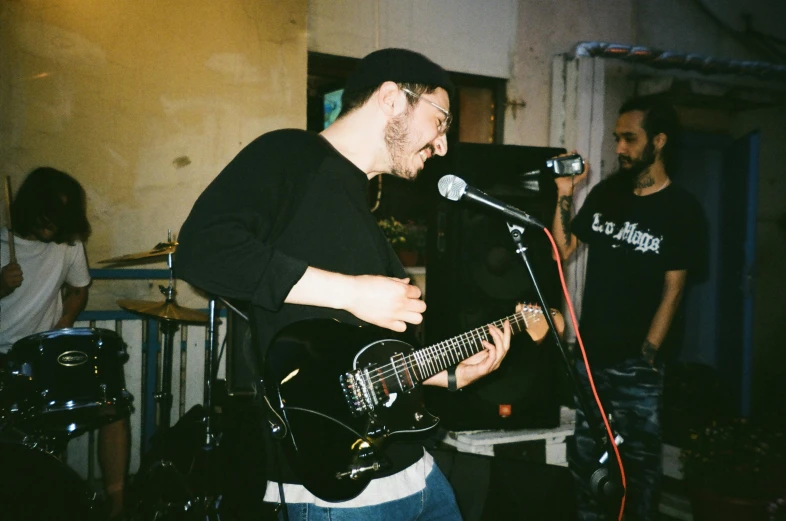 two men in front of a microphone with a guitar