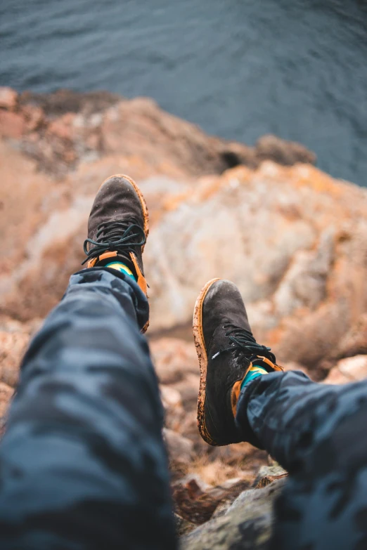 someone wearing black and blue hiking shoes standing on rocks