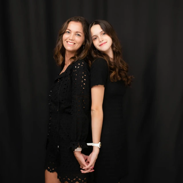 two women standing next to each other in front of a black backdrop