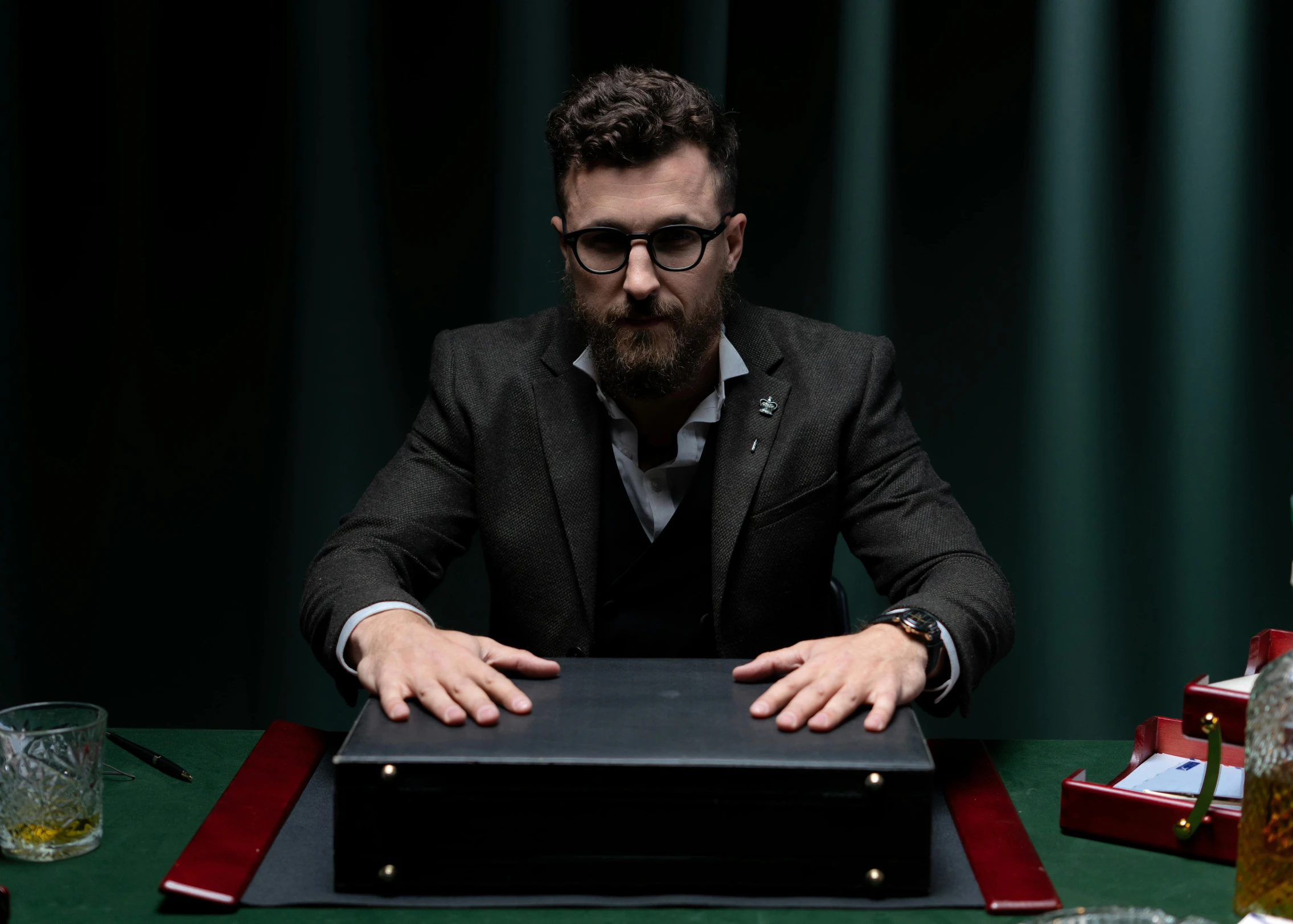 man sitting at table with glass on green cloth