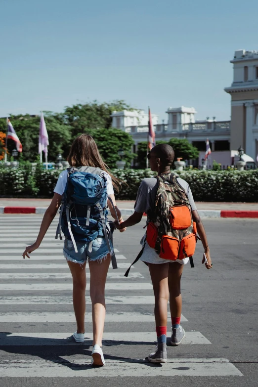 two girls walking with backpacks across a parking lot