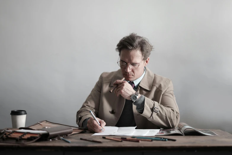 a man in suit sitting at desk writing on paper