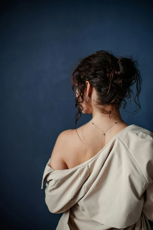 a woman wearing a beige dress with a necklace around her neck