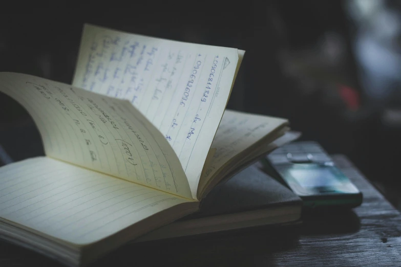 an open book sitting next to a cell phone