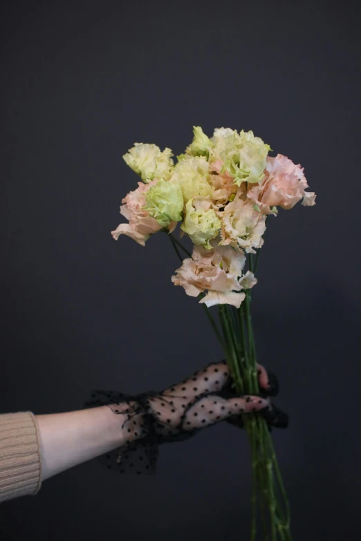 a hand holding flowers in a vase on top of a table