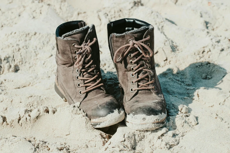 a pair of boots are standing on the sand