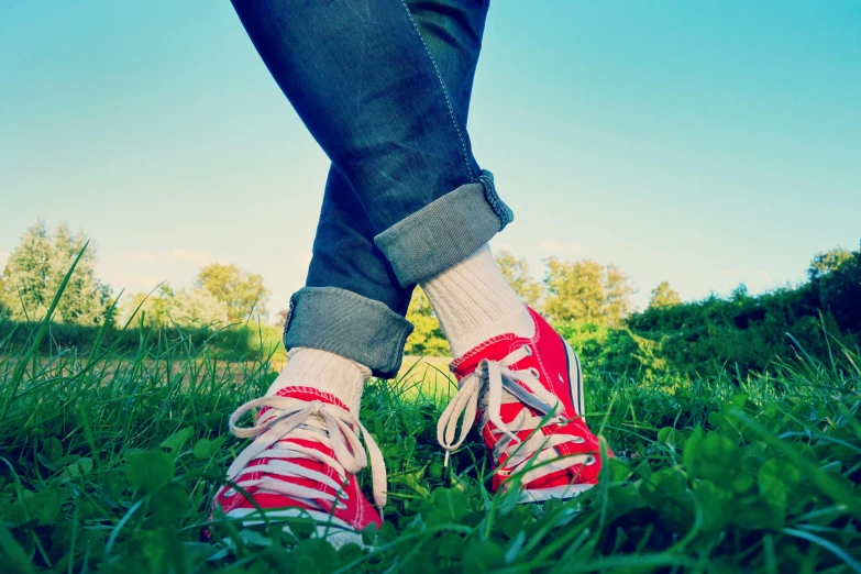 the legs and sneakers of a woman in the grass