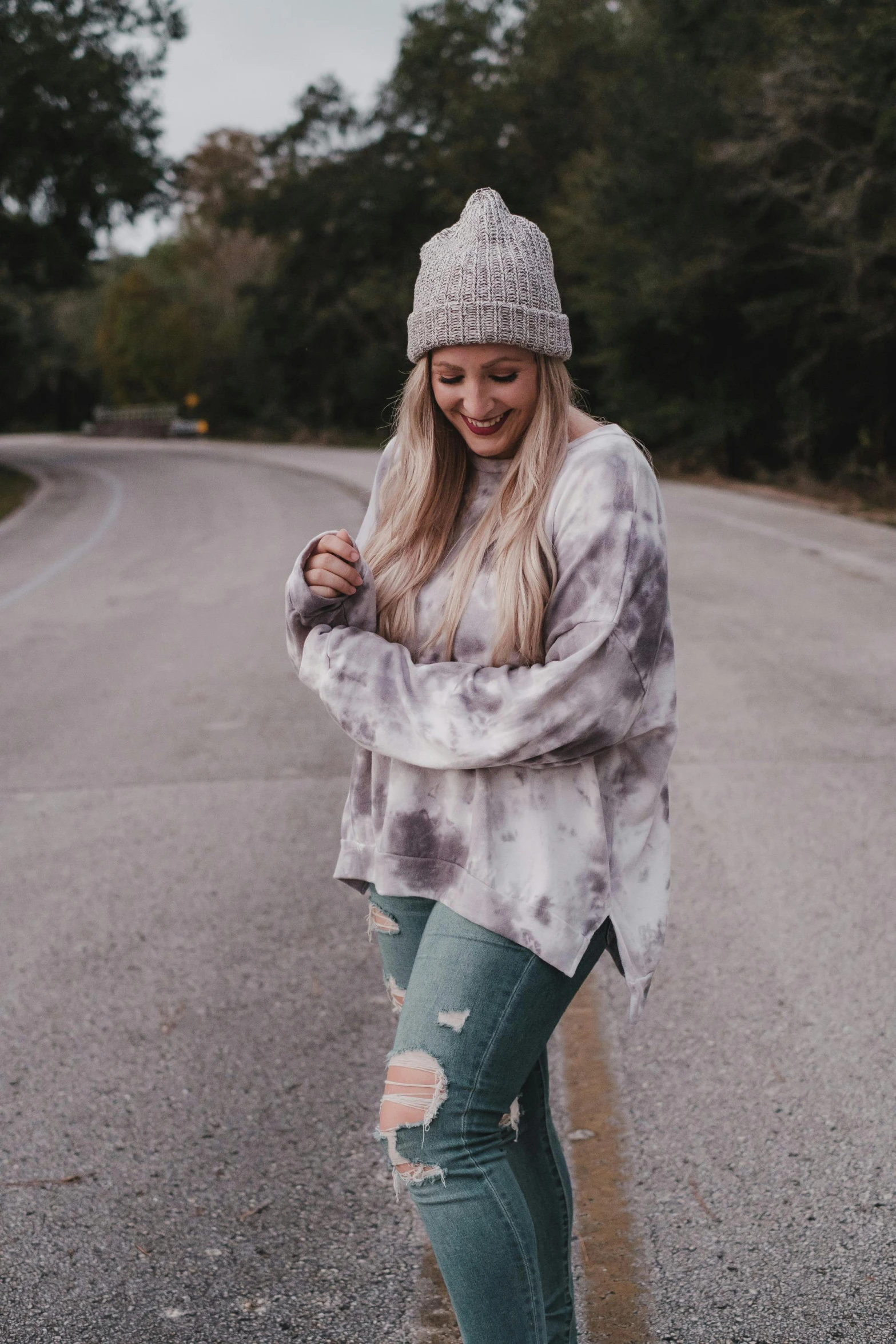 a woman in a gray and black sweater with jeans and a beanie