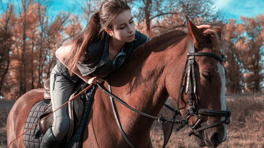 a woman sitting on the back of a brown horse