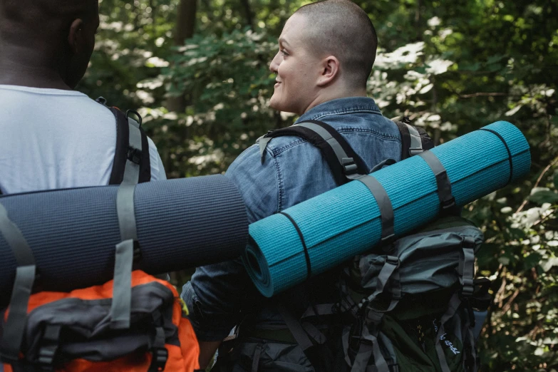 two men carry backpacks through a jungle