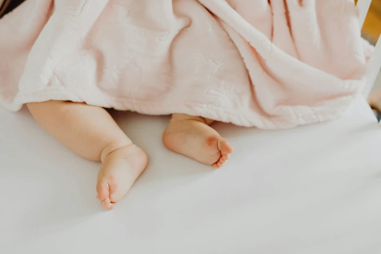 a young baby wrapped in a pink blanket laying on a bed