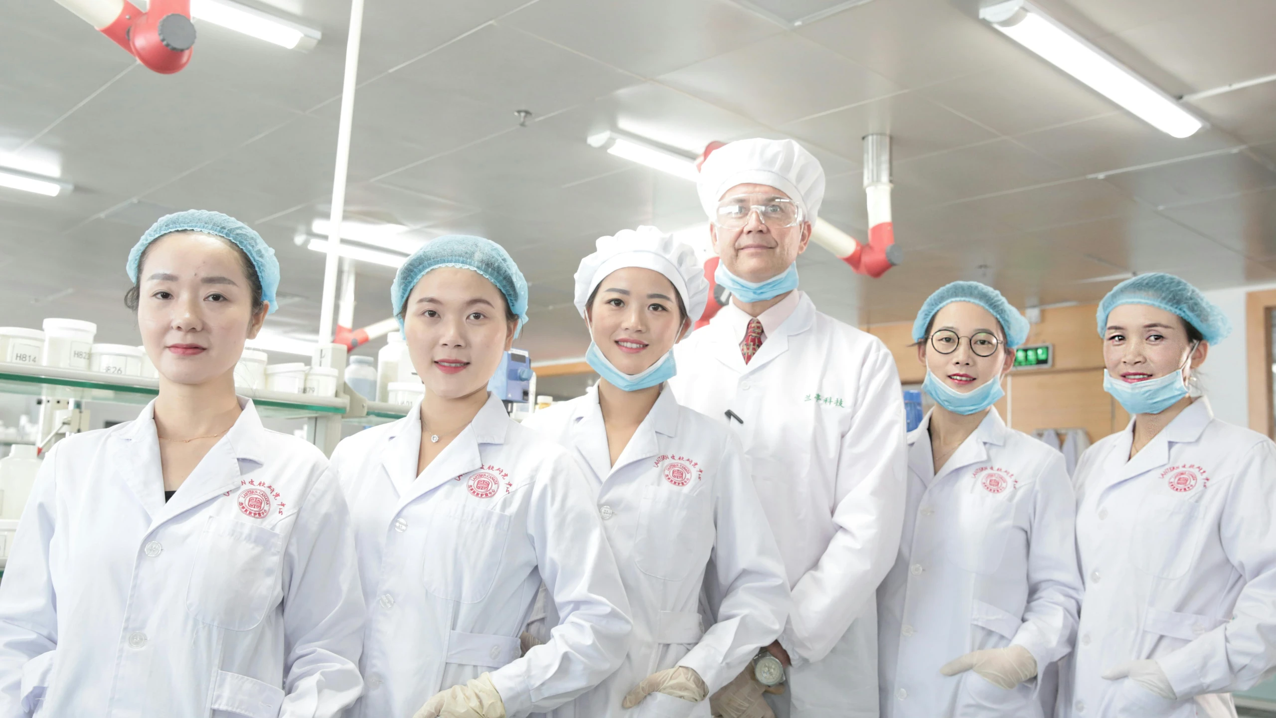 several people in white coat and medical gear in an office setting