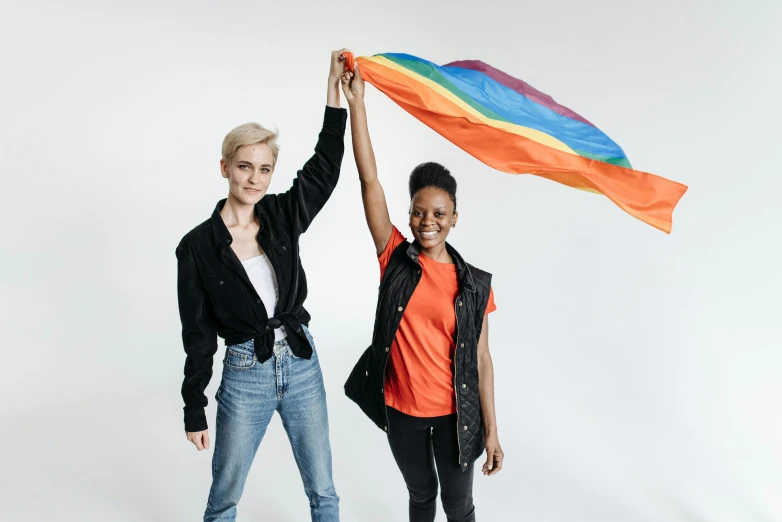 two women posing together with a colorful flag