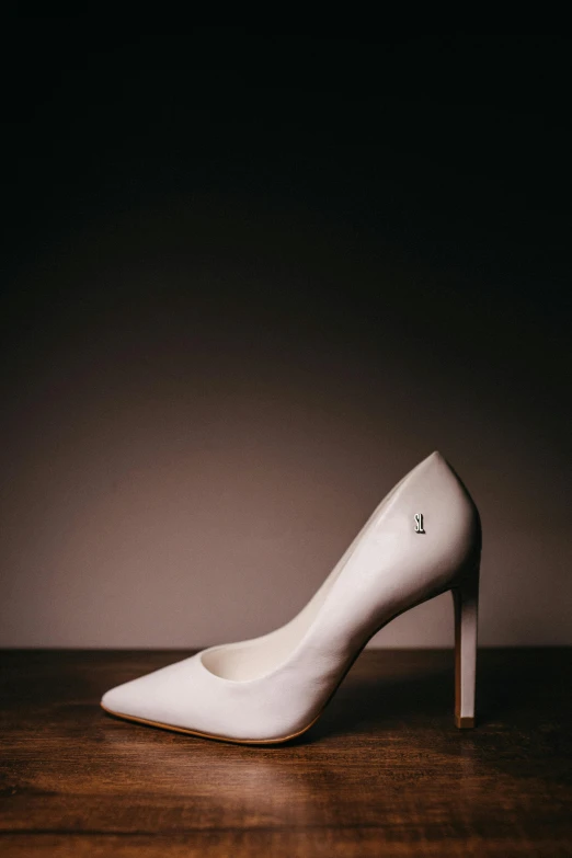 a high heeled white shoe is sitting on a wooden surface