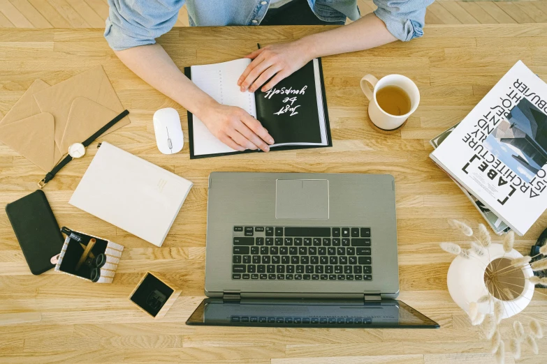 a person sitting at a table with their laptop and notebook