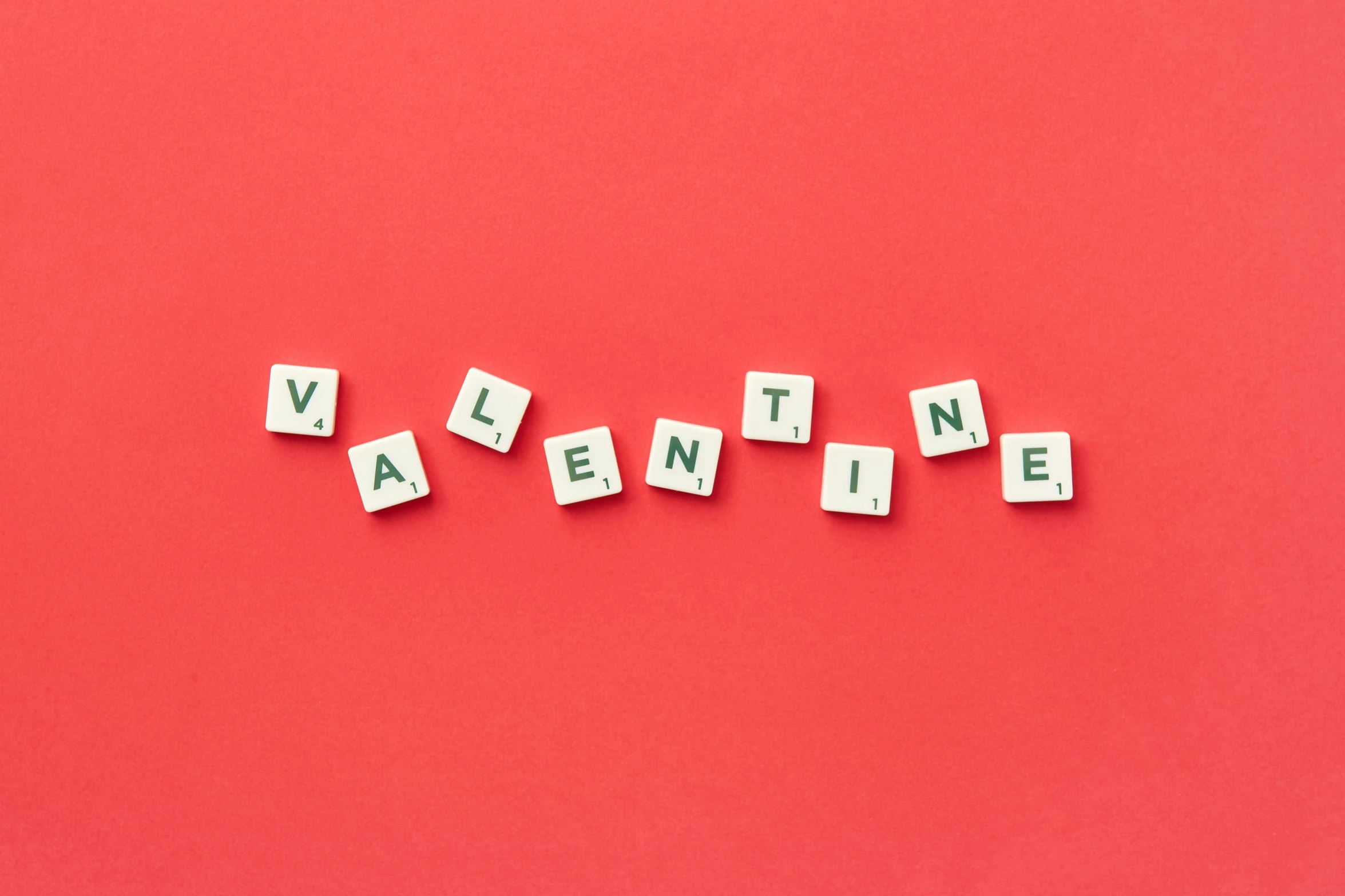 a group of scrabble blocks spelling the wordvalentne on a red background