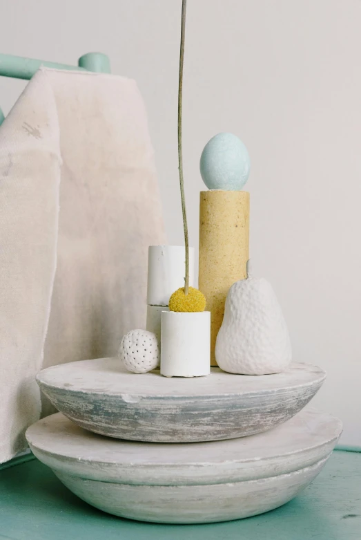 three round objects stand on a white surface near a cushion