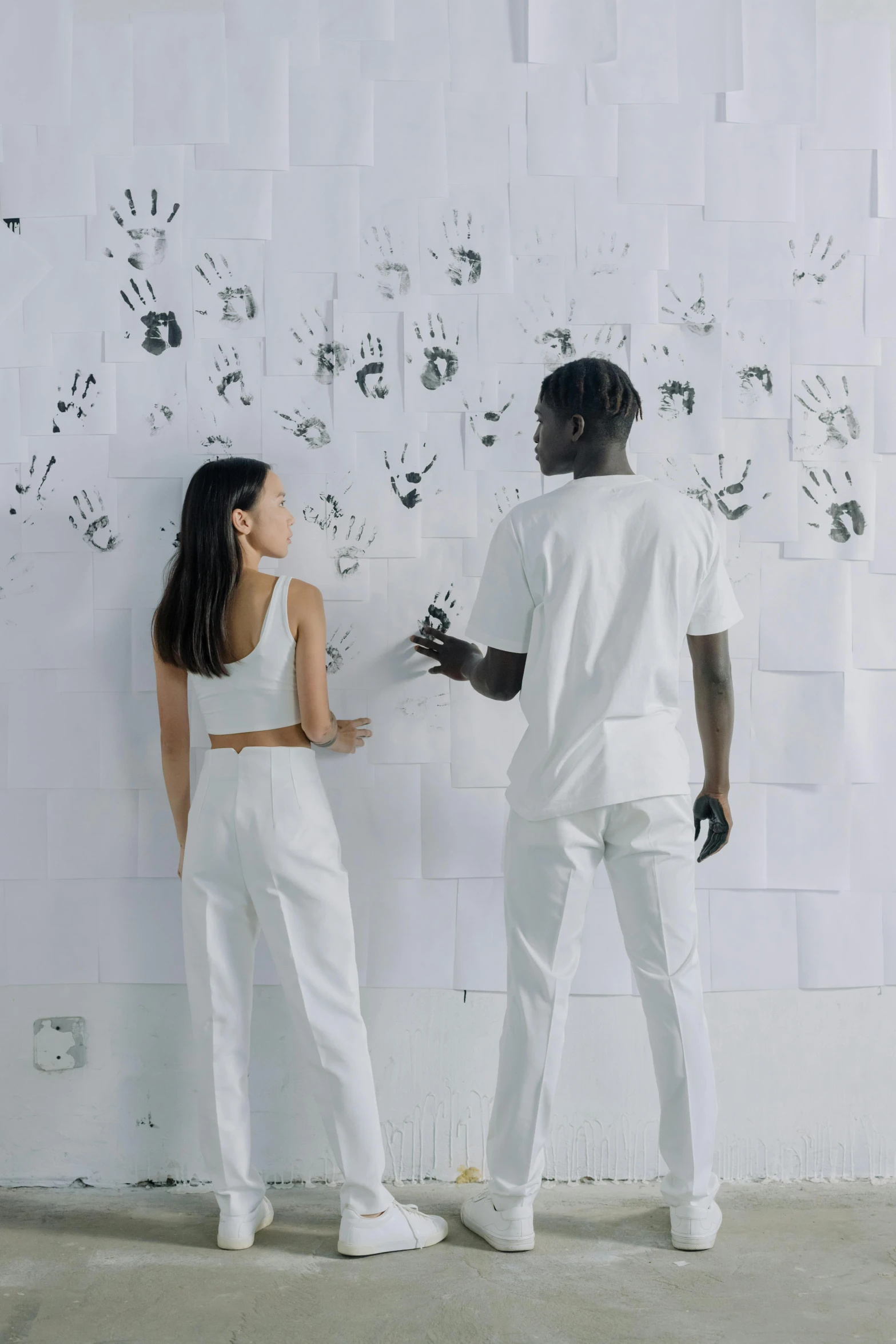 a man and woman putting together paper on a wall