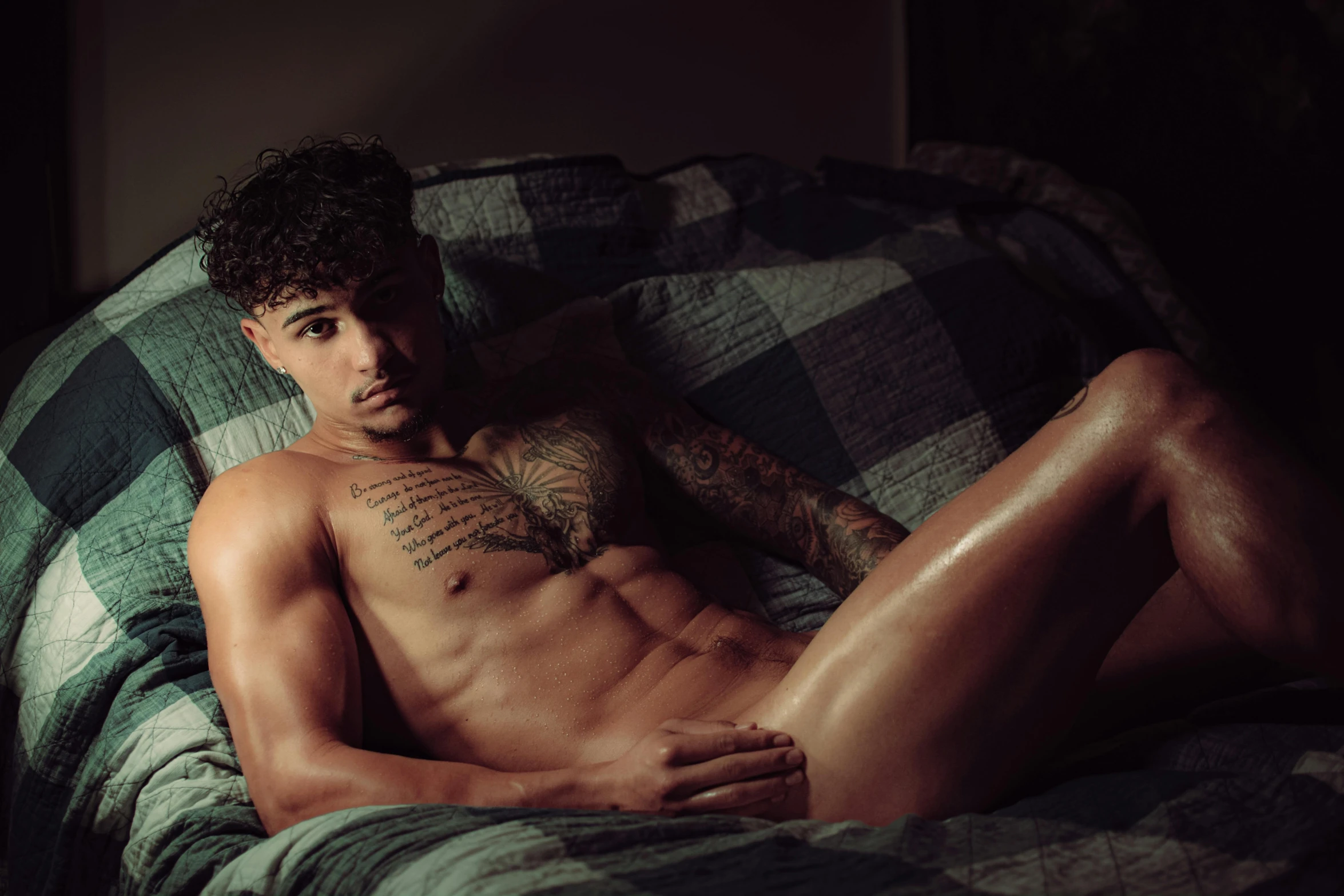 a shirtless man laying on a bed in the sunlight