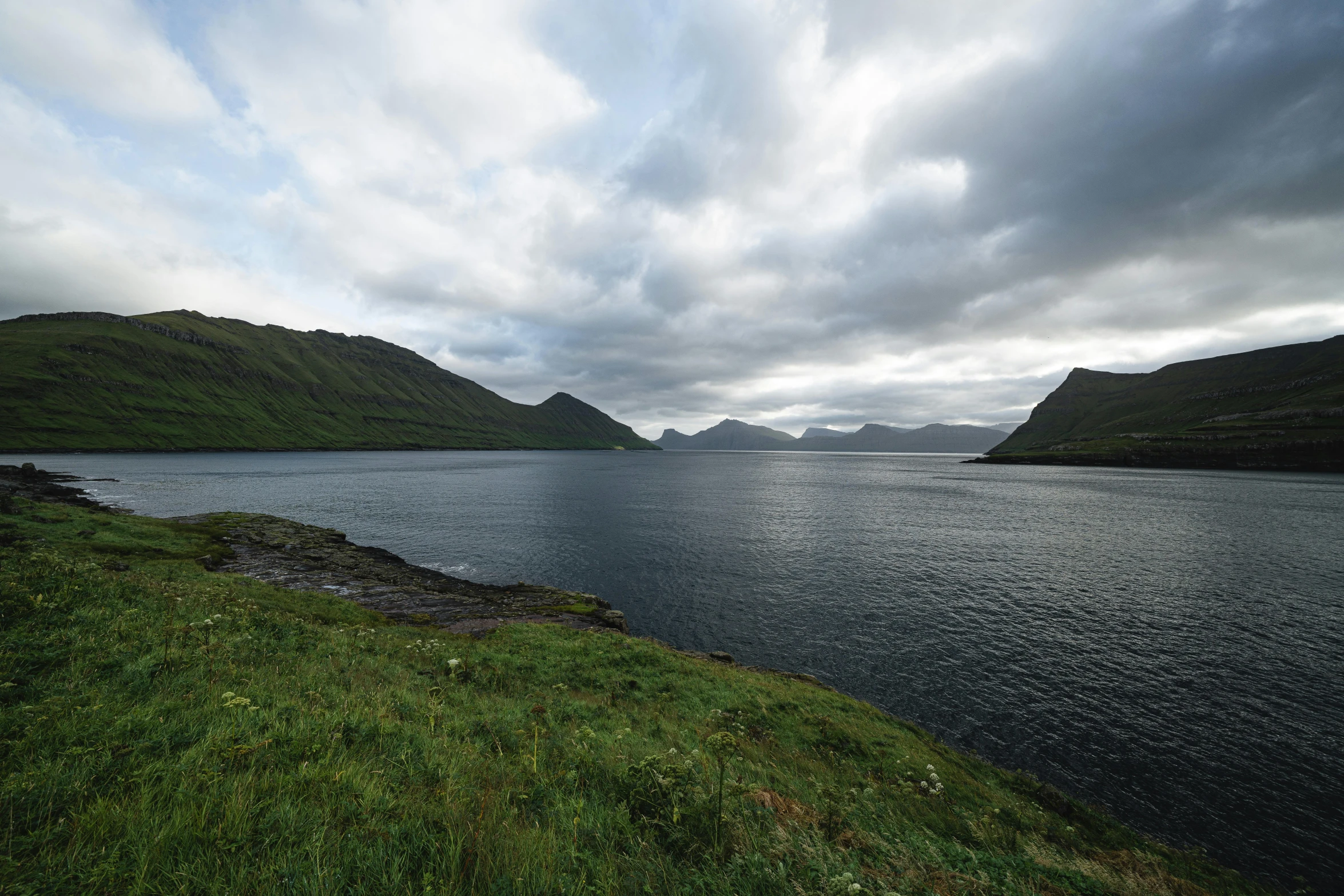 a view of the mountains of an open field across a lake