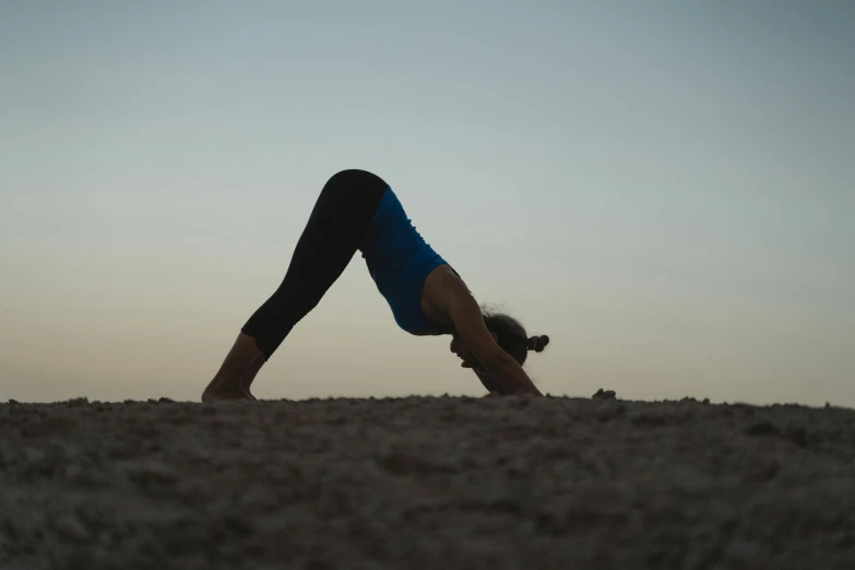 woman doing handstand on sand in the evening