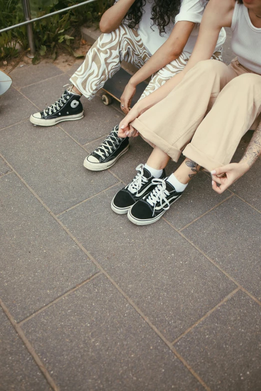 three people sitting on the ground and one is tying their shoes