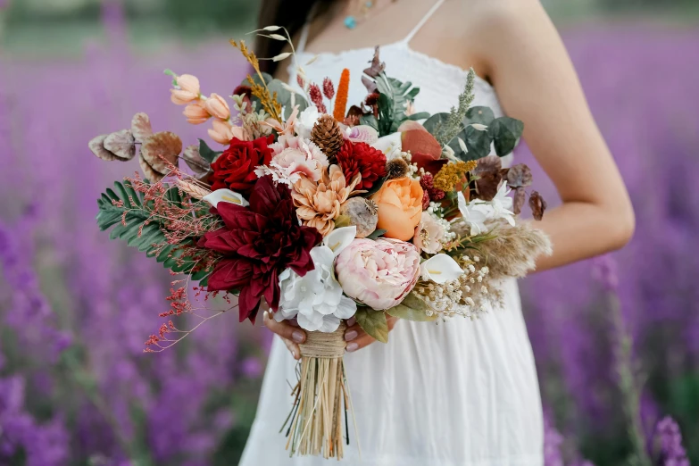 a woman holding a bouquet with colorful flowers