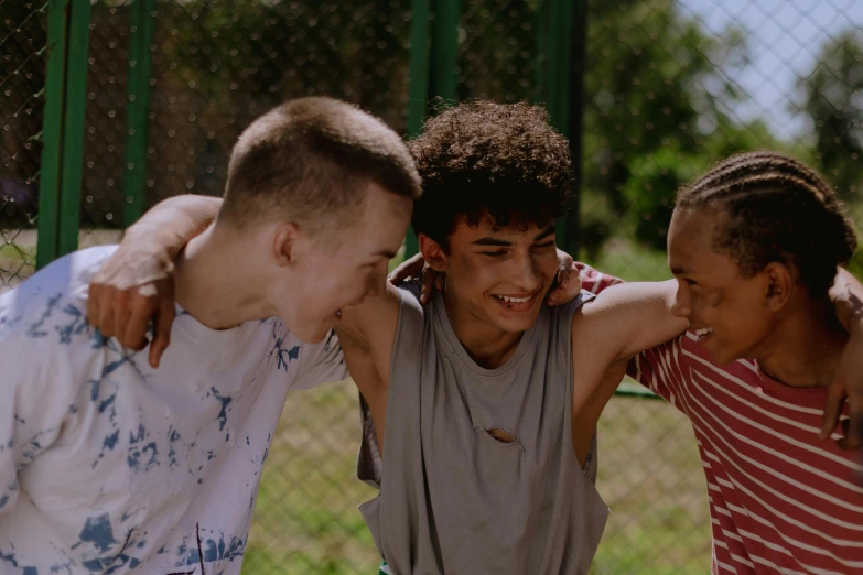 two teenage boys are laughing while the other is standing up